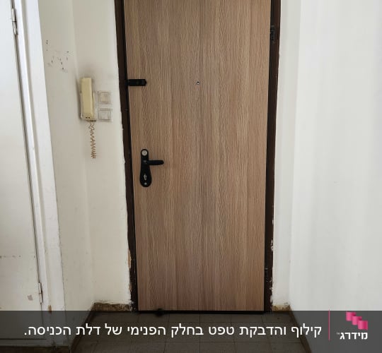 דלת עץ עם ידית שחורה ומסגרת כהה